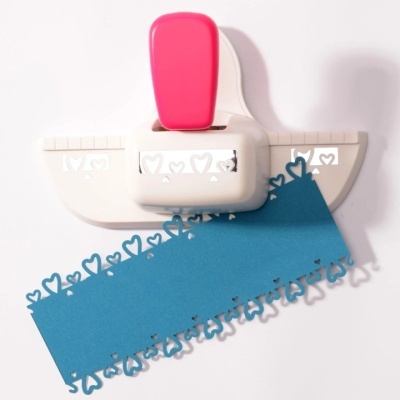 Perfurador de papel branco com alça rosa e padrão de corações em papel azul