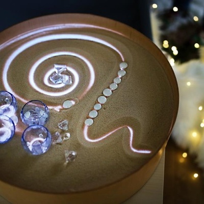 Relógio de areia com areia dourada e decoração com pedras e luzes cor-de-rosa