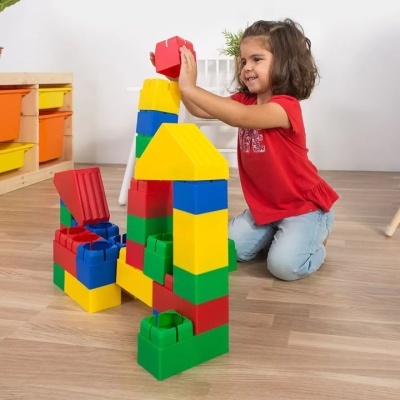 Criança a brincar com blocos de construção grandes coloridos no chão
