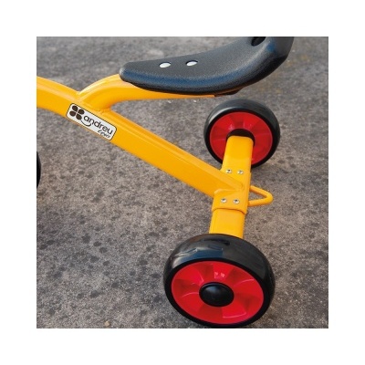 Carrinho ou brinquedo amarelo com rodas vermelhas e assento preto sobre chão cinzento