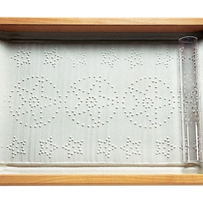 Tabuleiro de jogo infantil com símbolos perfurados e tubo de plástico