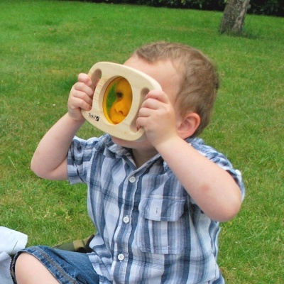 criança a segurar brinquedo de madeira com lentes coloridas