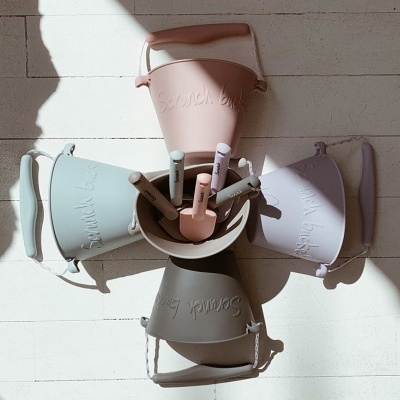 Baldes e pás de praia coloridos com inscrição Sand line em relevo