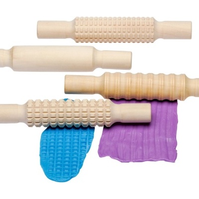 Rolos de massa de madeira com texturas e massas coloridas azul e roxa sobre fundo branco