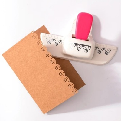 Perfurador de papel branco com pega rosa e padrão floral recortado em cartão castanho