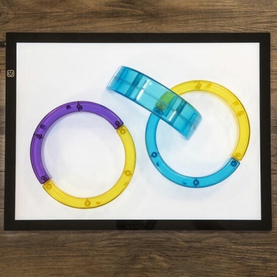 Pulseiras coloridas em plástico transparente sobre quadro branco com moldura preta em mesa de madeira