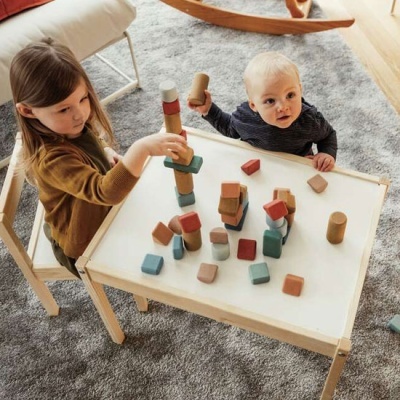 Crianças a brincar com blocos de madeira coloridos numa mesa branca