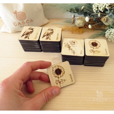 Blocos de madeira com desenho gravado de pássaro, flor e girassol sobre mesa de madeira clara