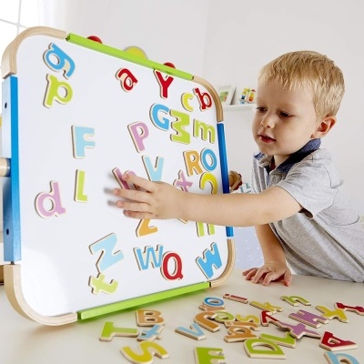 Quadro branco magnético com letras coloridas e criança a brincar