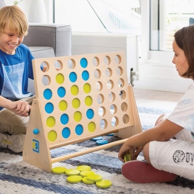 Crianças a jogar um jogo de tabuleiro de madeira com discos coloridos em casa