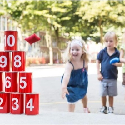 Crianças a jogar com blocos vermelhos numerados ao ar livre.
