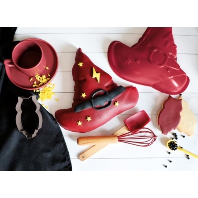 Sapatos vermelhos em forma de chapéu de bruxa com decoração amarela e utensílios de cozinha.