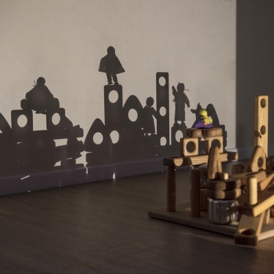 Brinquedo de construção em madeira com sombras projetadas na parede