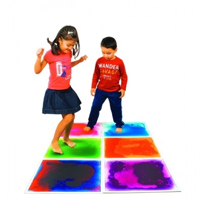 Crianças brincando em painéis quadrados coloridos no chão