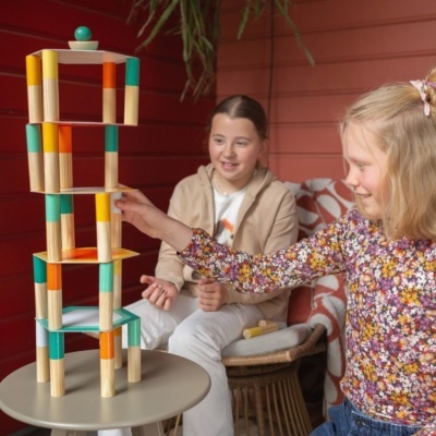 Brinquedo em madeira colorida para empilhar numa mesa com duas crianças a brincar