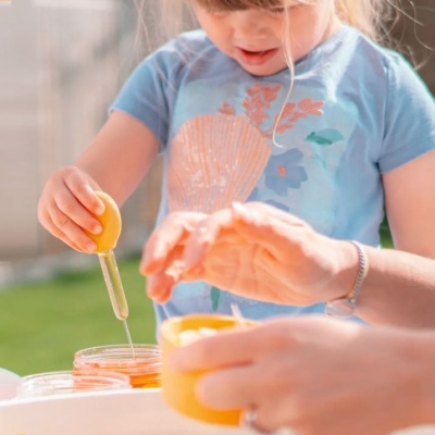 Criança a usar conta-gotas amarelo em frasco transparente ao ar livre