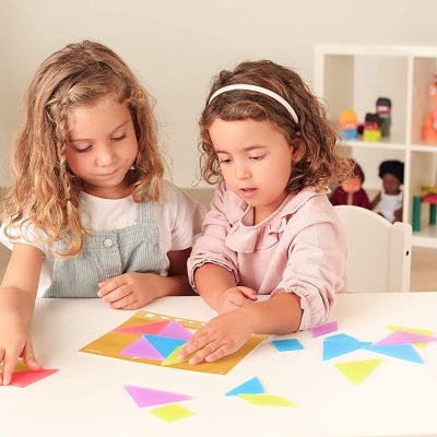Crianças a brincar com peças coloridas de vidro em mesa branca