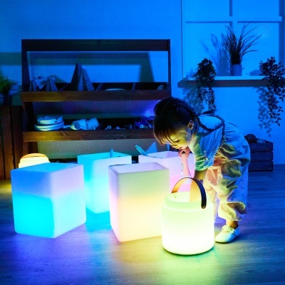 Cubo de luzes coloridas e lanterna com criança num ambiente interior