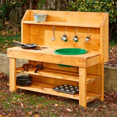 Bancada de madeira infantil com lava-louça verde e utensílios de cozinha ao ar livre