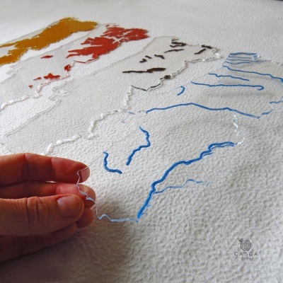 Peças de acrílico transparentes com linhas coloridas, mão segurando uma peça, sobre superfície branca