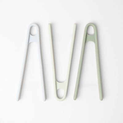 Três pinças de cozinha em silicone e plástico em branco, creme e verde claro