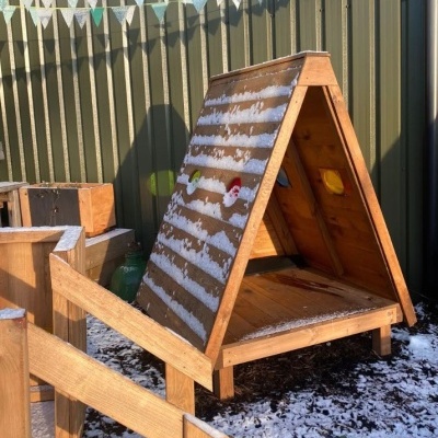 Abrigo triangular de madeira com decoração de Natal e neve