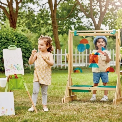 Duas crianças a brincar com cavaletes de madeira em jardim verde