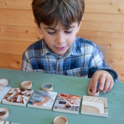 Criança a jogar com peças de madeira e cartas de imagens diversas numa mesa verde
