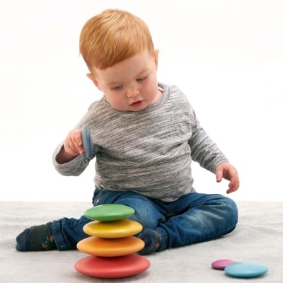 Criança a brincar com brinquedo de empilhar discos coloridos