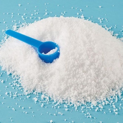 Pó branco granulado com colher de plástico azul