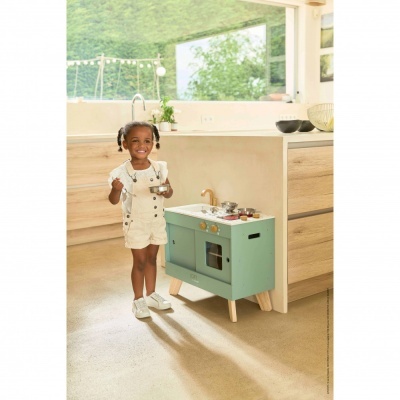 Criança com cozinha de brinquedo verde em cozinha moderna