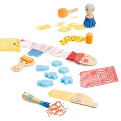 Brinquedos de madeira e esponja para pintura com figuras coloridas e pincéis sobre fundo branco