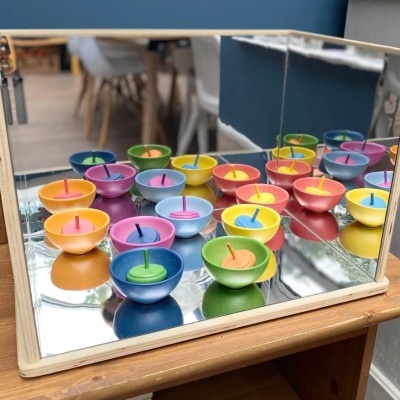 Pequenas velas coloridas em recipientes redondos sobre base espelhada