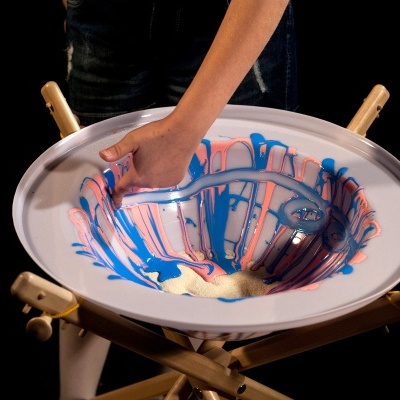 Bandeja redonda branca com padrões coloridos em azul, rosa e bege sobre suporte de madeira