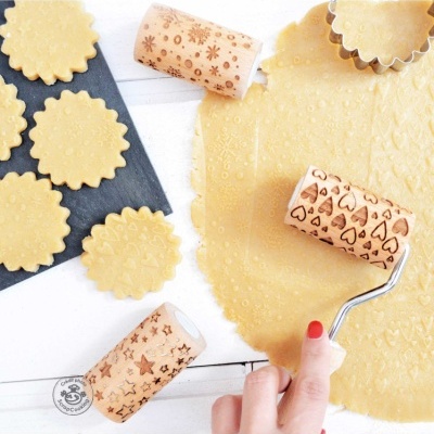 Rolo decorativo de massa e bolachas decoradas com padrões em superfície branca