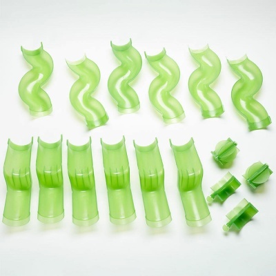 Peças plásticas verdes curvas e segmentadas sobre superfície branca