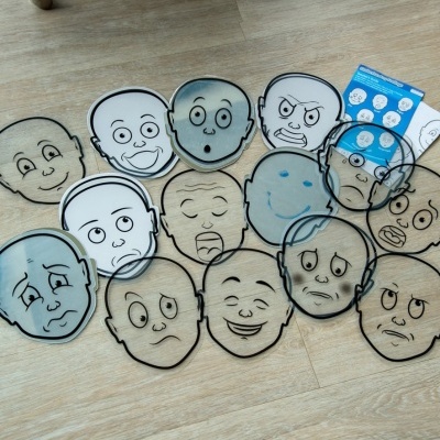 Máscaras de plástico transparente com diferentes expressões faciais em chão de madeira