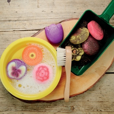 Produtos de limpeza coloridos em bacia e pá sobre tábua de madeira