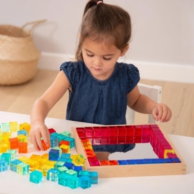 Criança a brincar com blocos de construção coloridos em tabuleiro de madeira