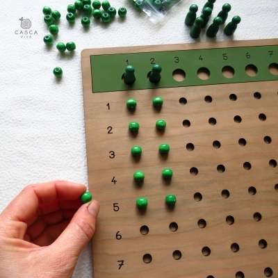 Tabuleiro de madeira com bolas verdes e numeração para jogo ou aprendizagem.