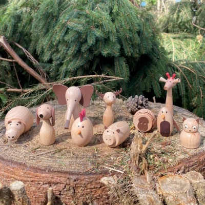 Figuras de animais de madeira simples sobre um tronco com coníferas ao fundo