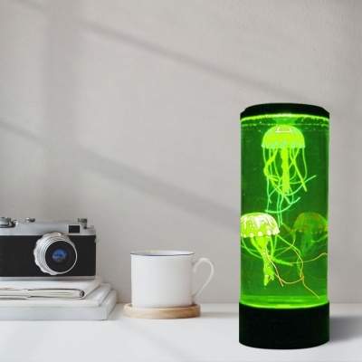 Câmara fotográfica, chávena branca e aquário cilíndrico com medusas iluminado a verde