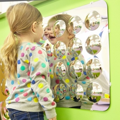 Painel interativo com espelhos convexos prateados para crianças em parede verde