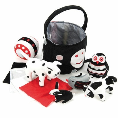 Brinquedos de peluche em preto, branco e vermelho com bolsa preta decorada com rosto sorridente.