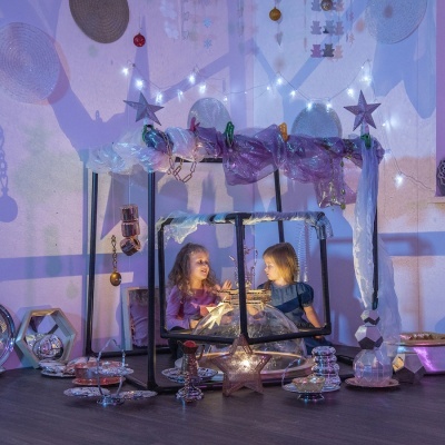 Tenda infantil com crianças, luzes e decoração de estrelas em ambiente interior