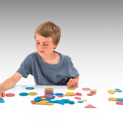 Criança a brincar com peças geométricas coloridas de madeira.