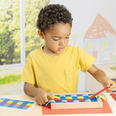 Criança brincando com brinquedo tátil colorido numa mesa com luz natural