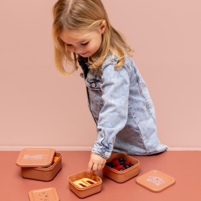 Caixas de armazenamento quadradas terracota com frutas e snacks, criança loira pega comida