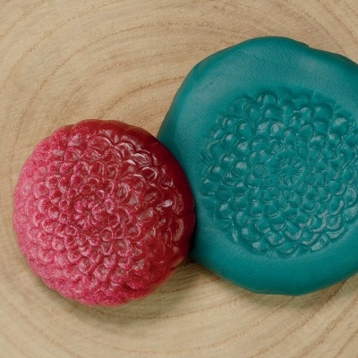 Sabonete artesanal vermelho e prato azul com padrões florais sobre madeira clara