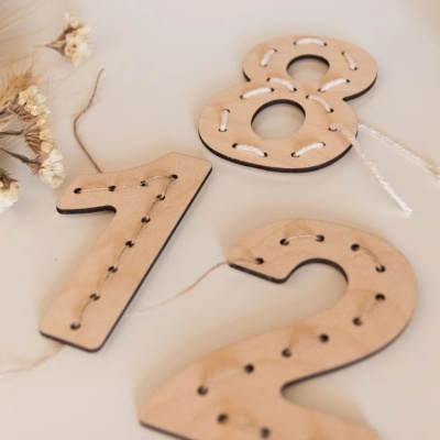 Números decorativos de madeira com cordão entrelaçado sobre superfície branca com flores secas